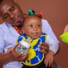 Baby wearing a blue giraffe bib while being fed
